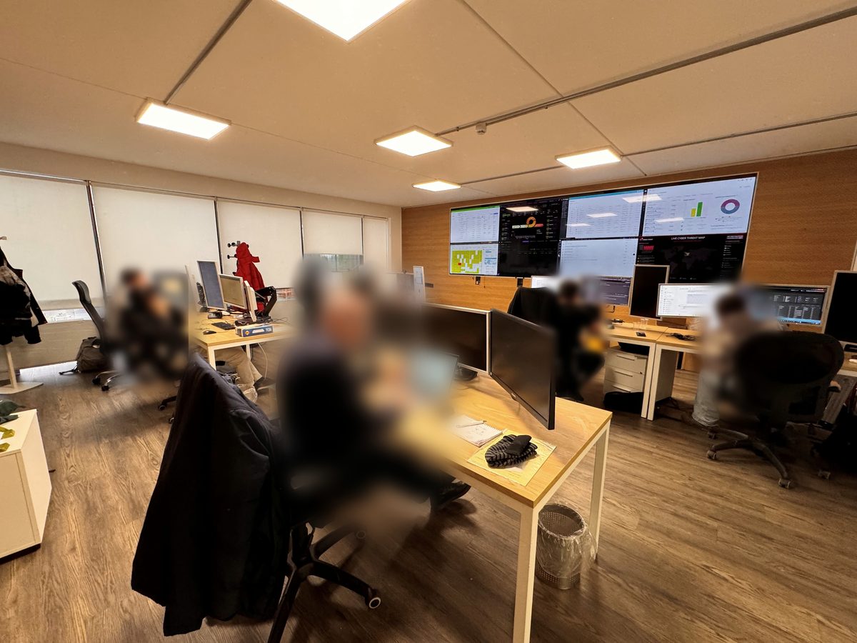 La control room di NSI Advisor ad Assago: analisti al lavoro davanti alla parete di monitor con le dashboard di NOC e SOC.